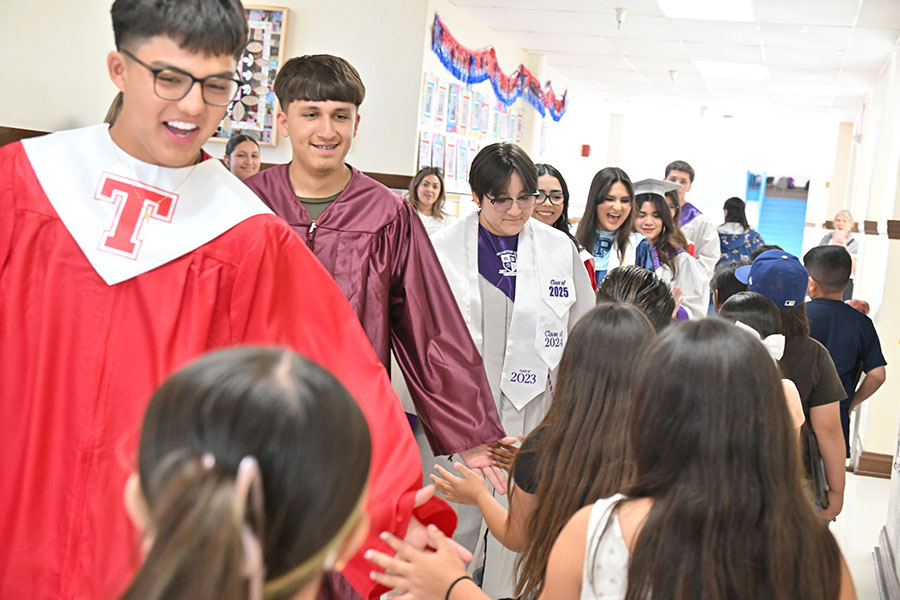 Seniors in their gowns walk the hallways, giving elementary students high fives