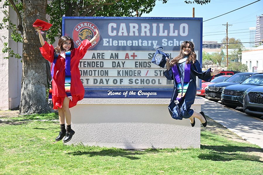Two graduating seniors jump in front of the Carrillo marquee in their caps and gowns
