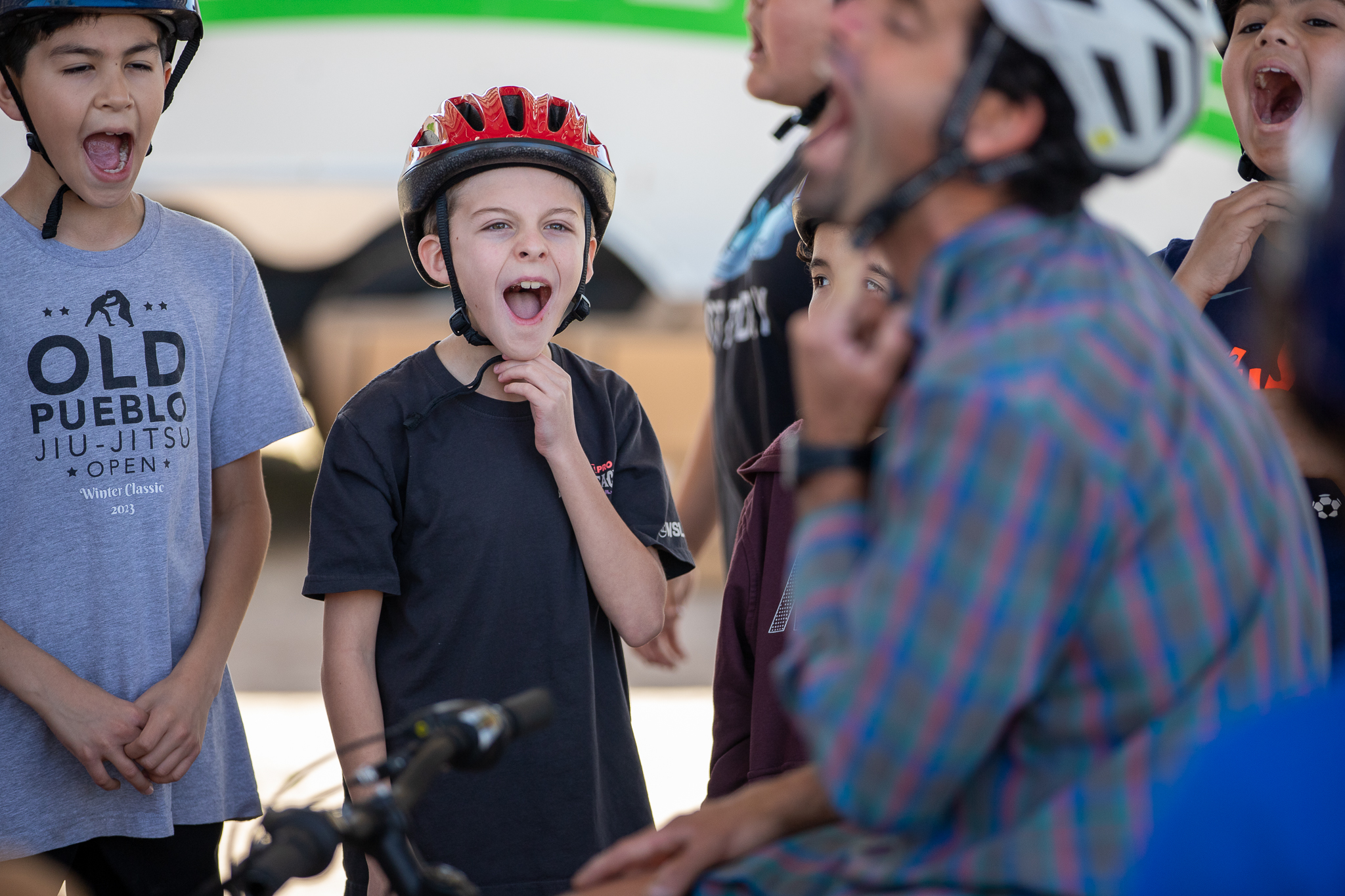 A group of boys wearing bike helmets yell excitedly