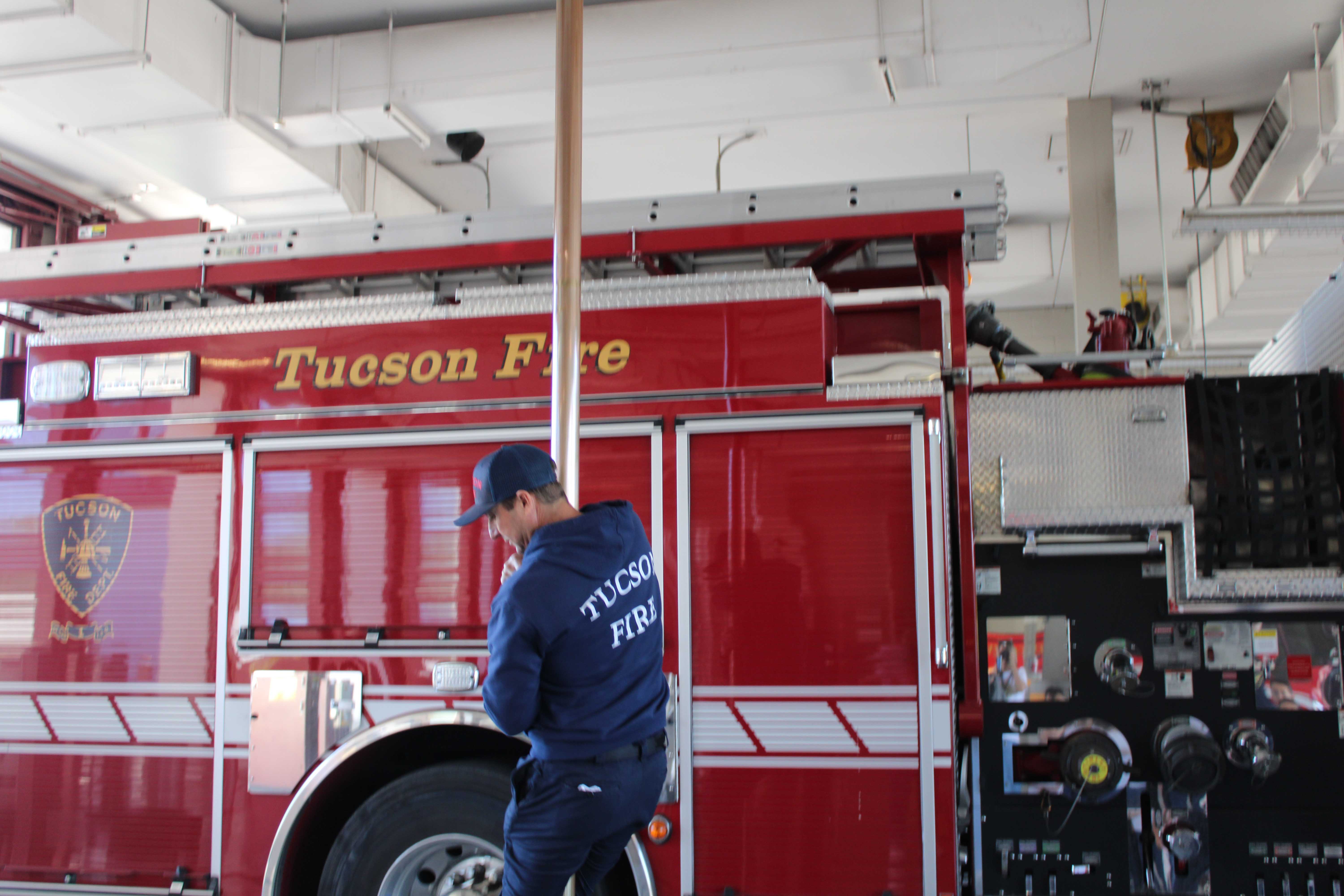 A firefighter shows students the fire pole