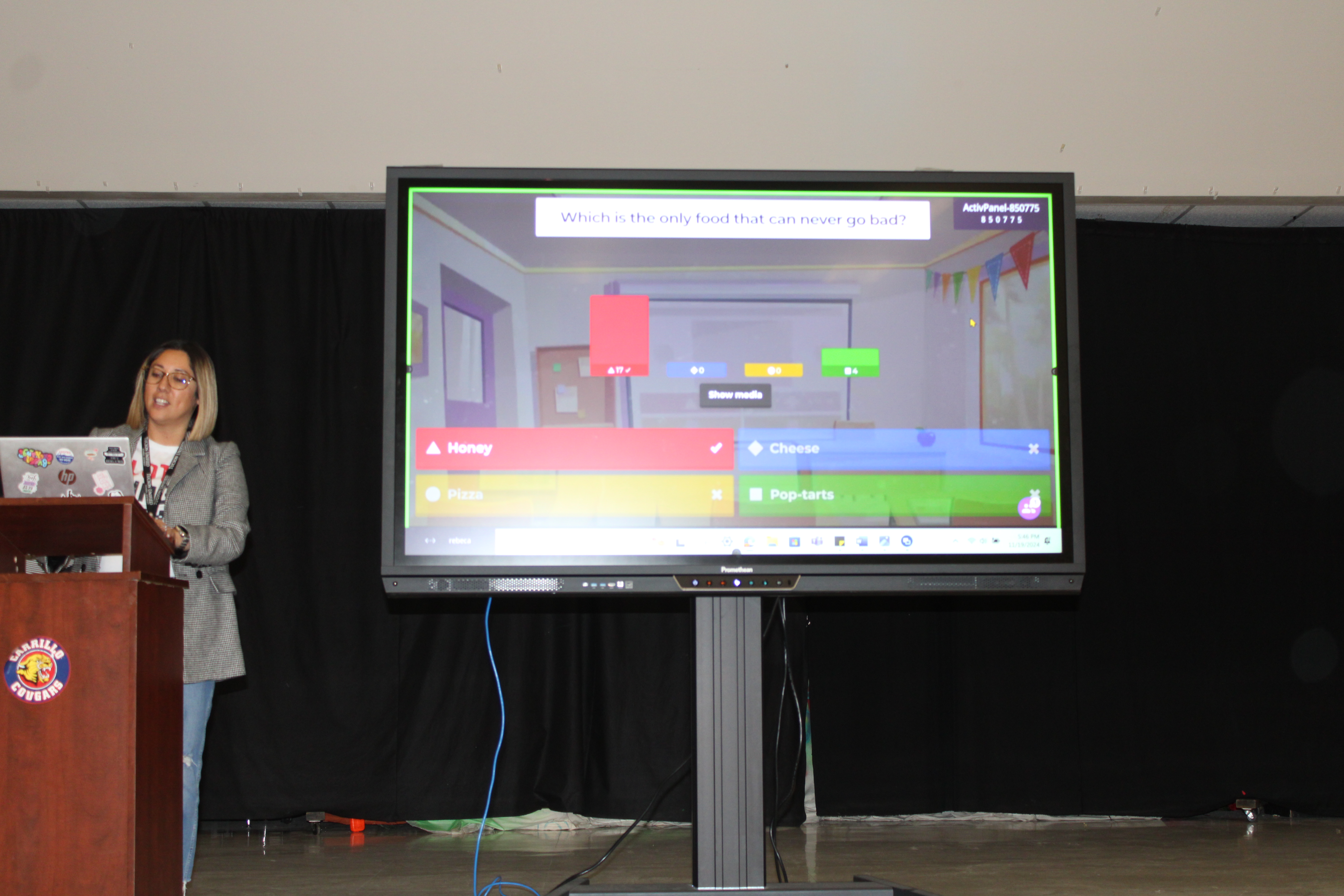 A woman stands next to a SmartBoard with a game screen