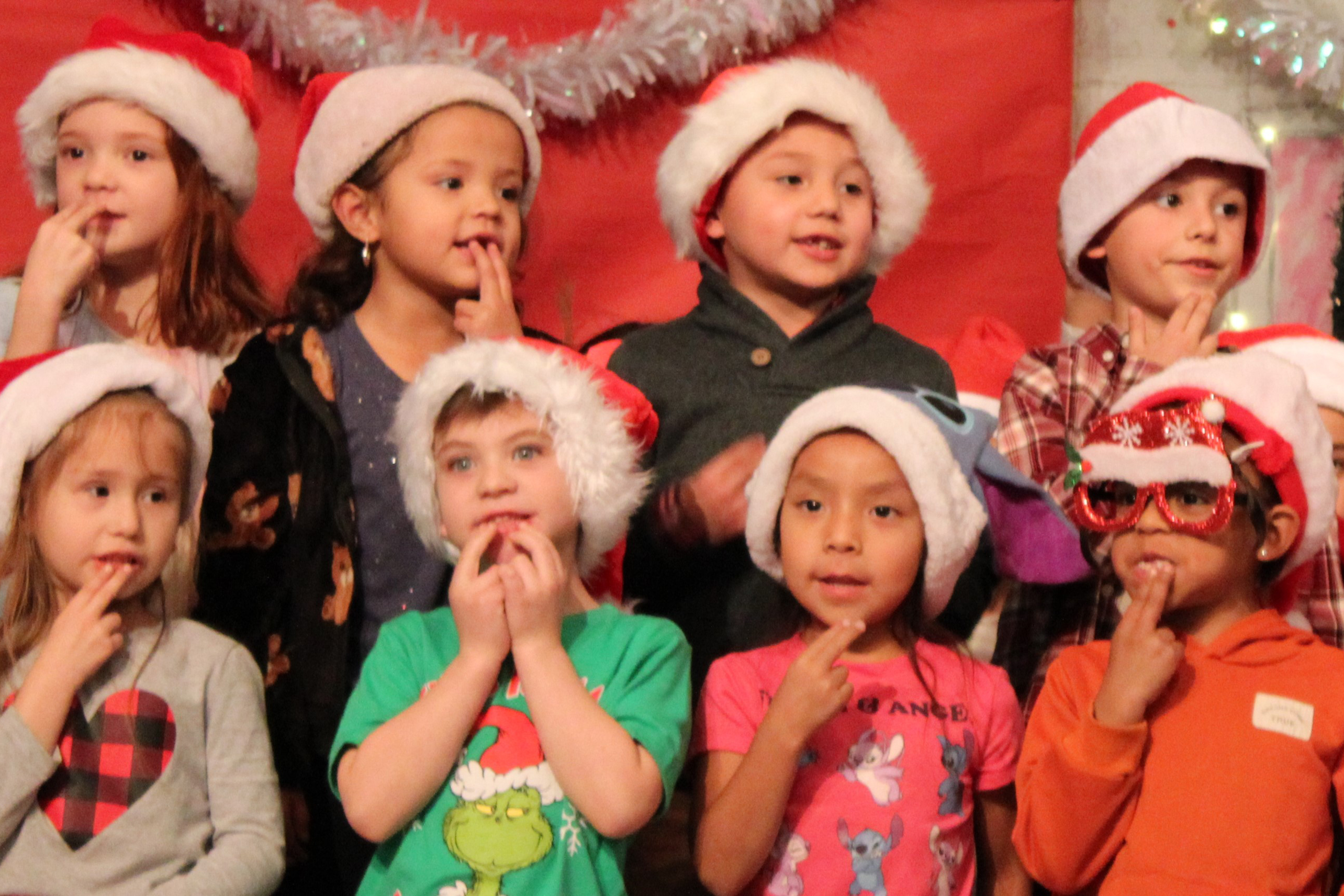 Eight students in Santa hats sing a song