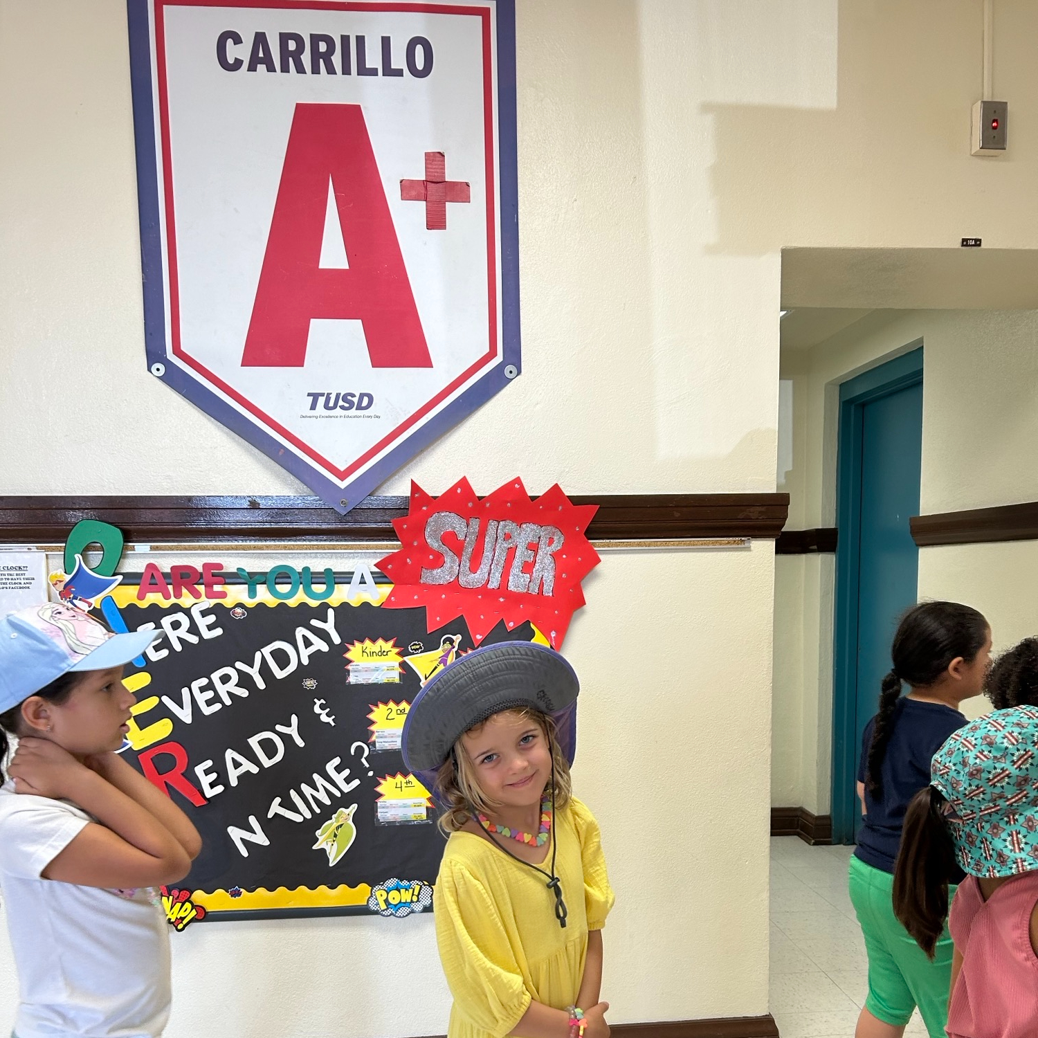 A girl in a cowboy hat smiles in front of the Carrillo A banner