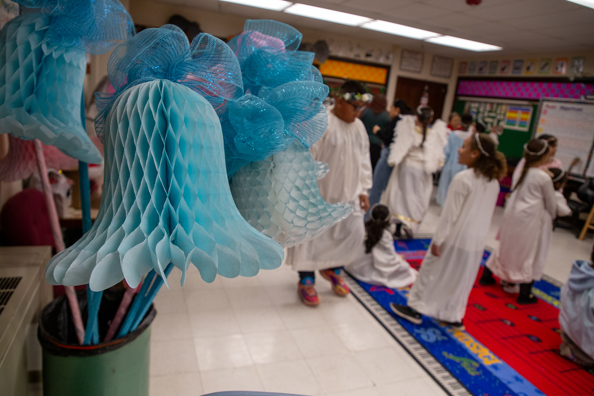 Students in angel costumes get ready for the procession, with big blue paper bells in the foreground