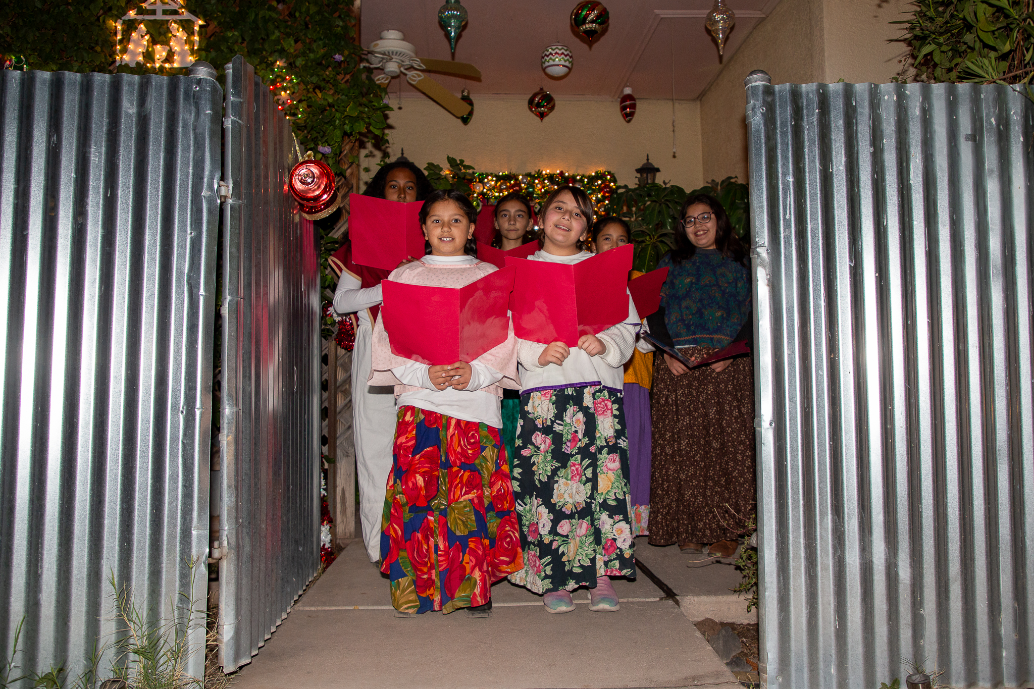 A group of girls holding red folders get ready to sing