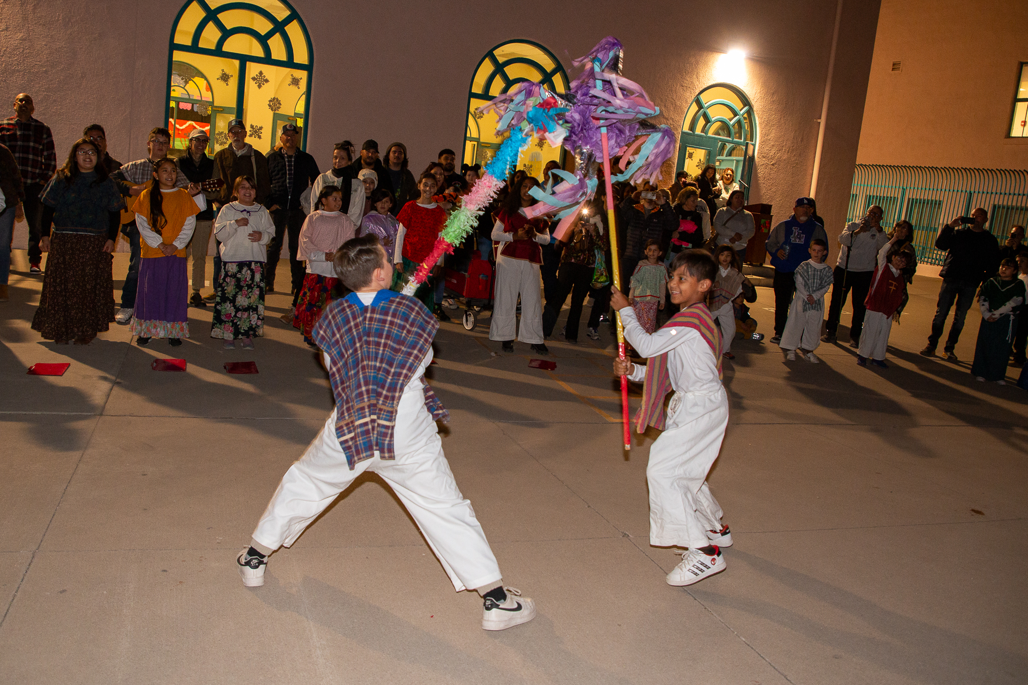 Two boys holding pinatas pretend to battle each other