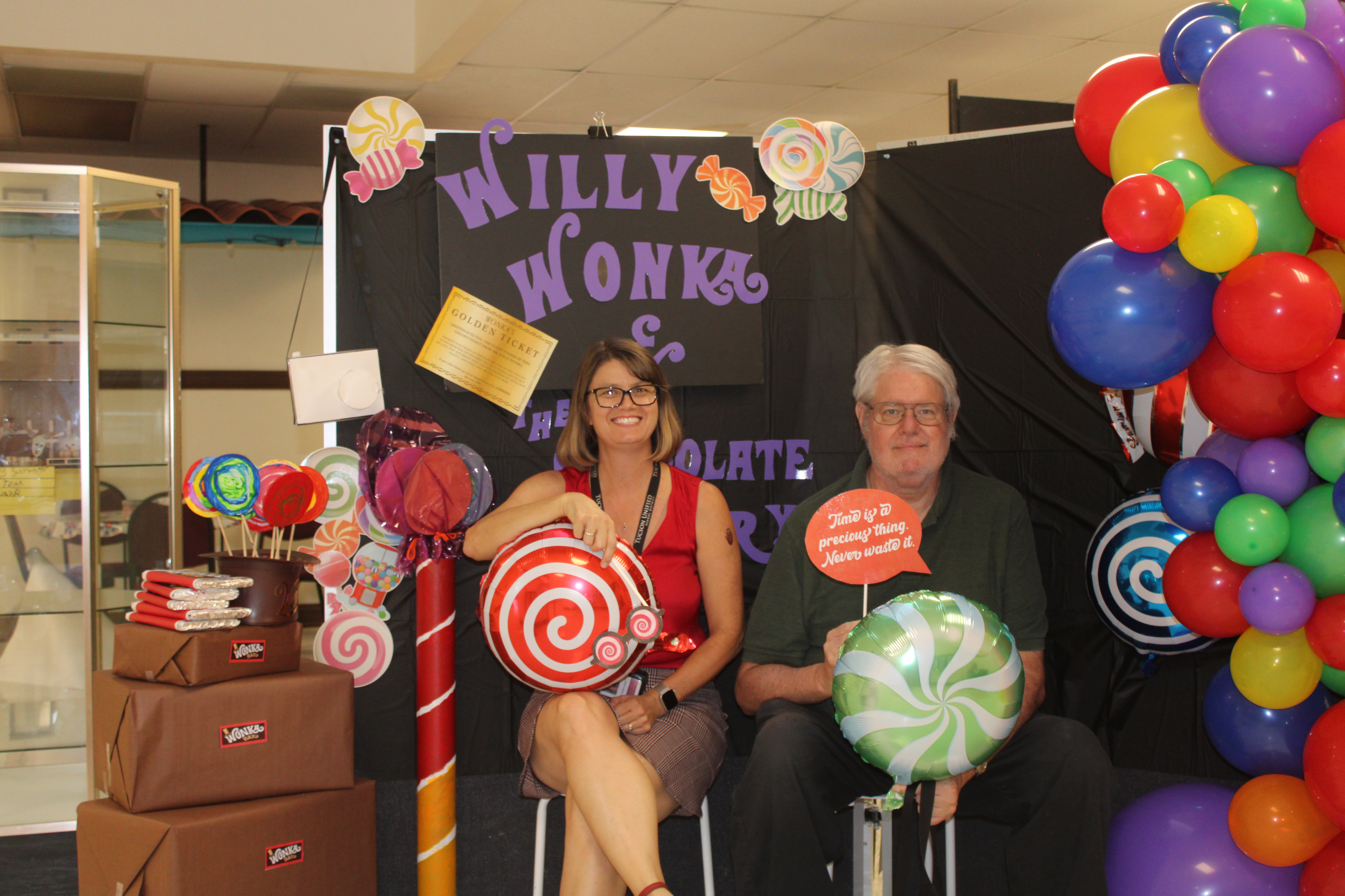 Carrillo's principal and a staff member pose with giant lollipops in front of the Willy Wonka display