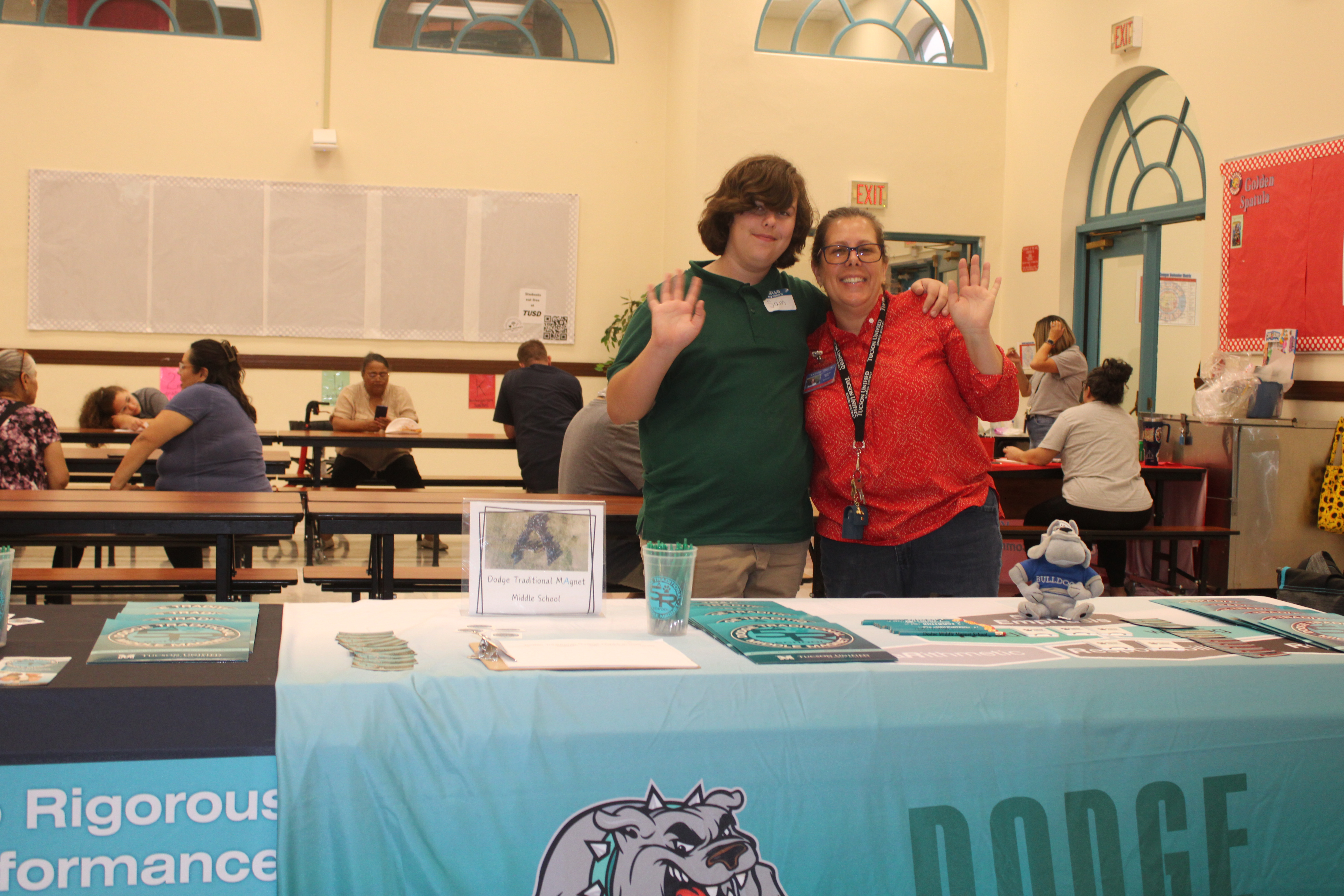 Two staff members wave from their table