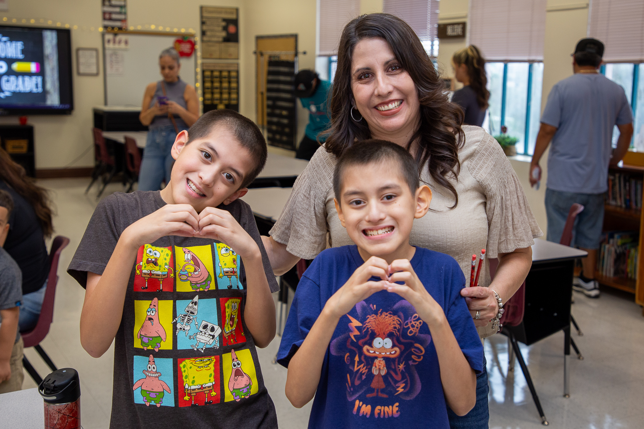 A mom smiles with her two sons making heart hands