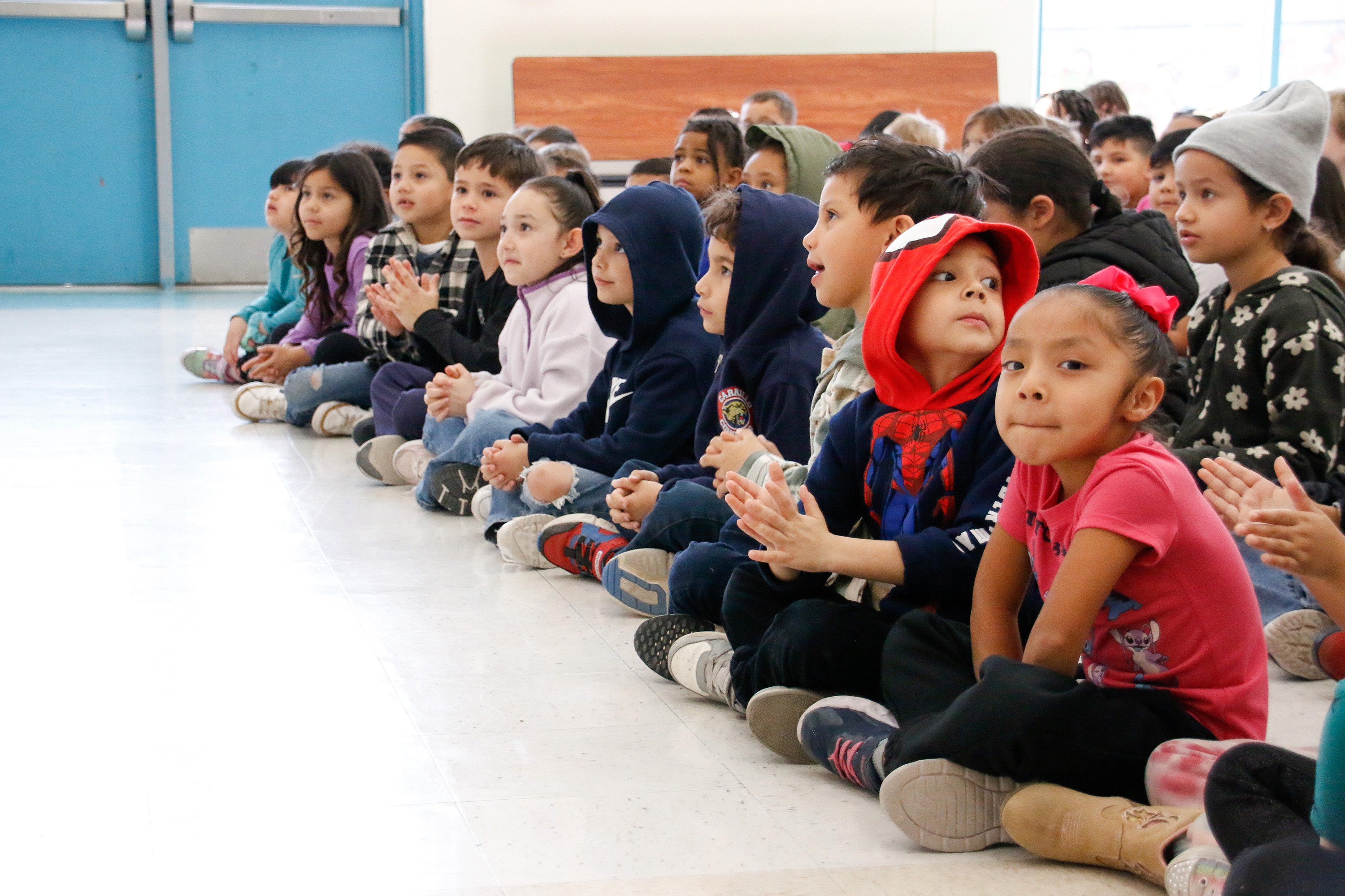 Students sit on the floor to listen to a story