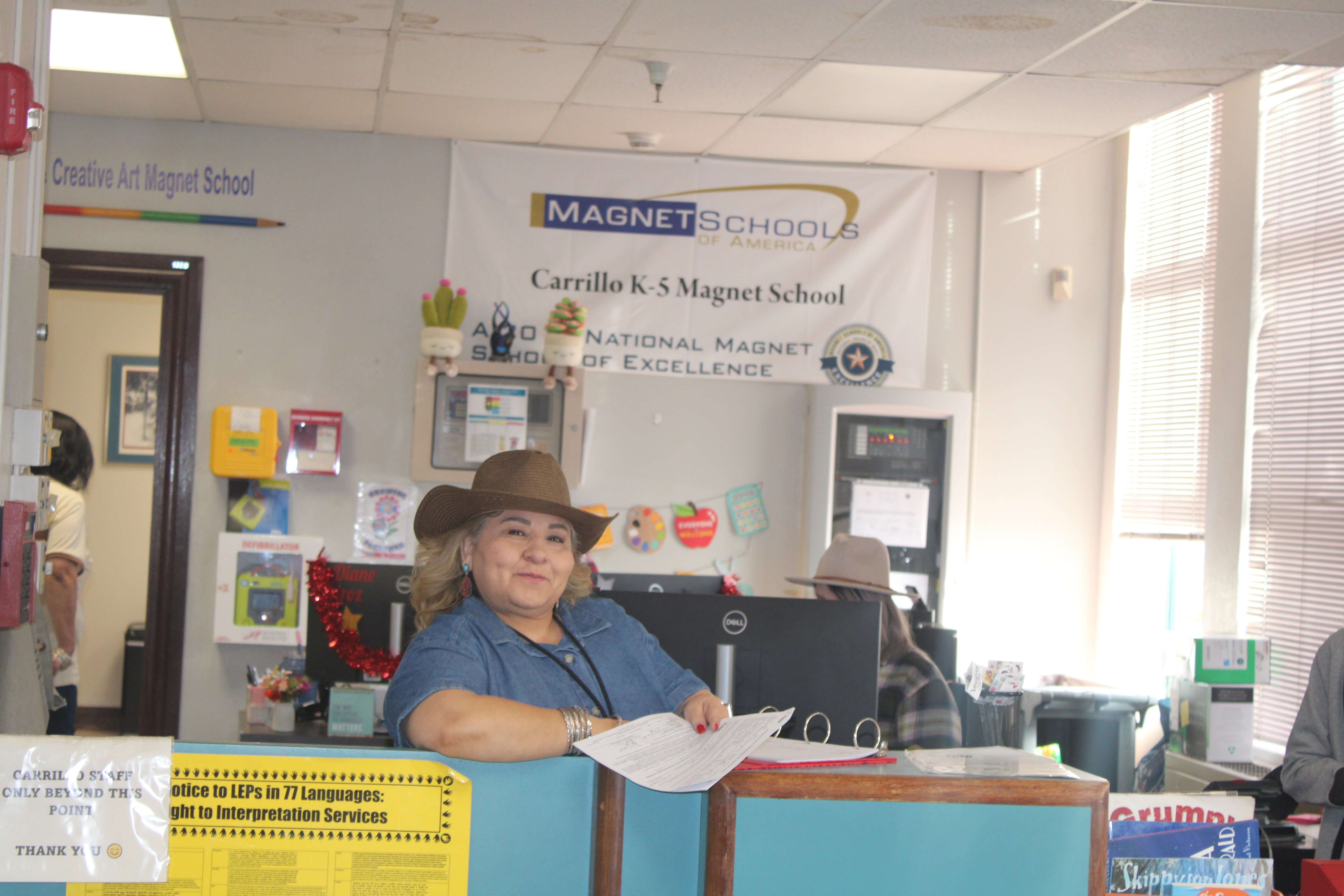 A woman in a cowboy hat smiles at the front desk