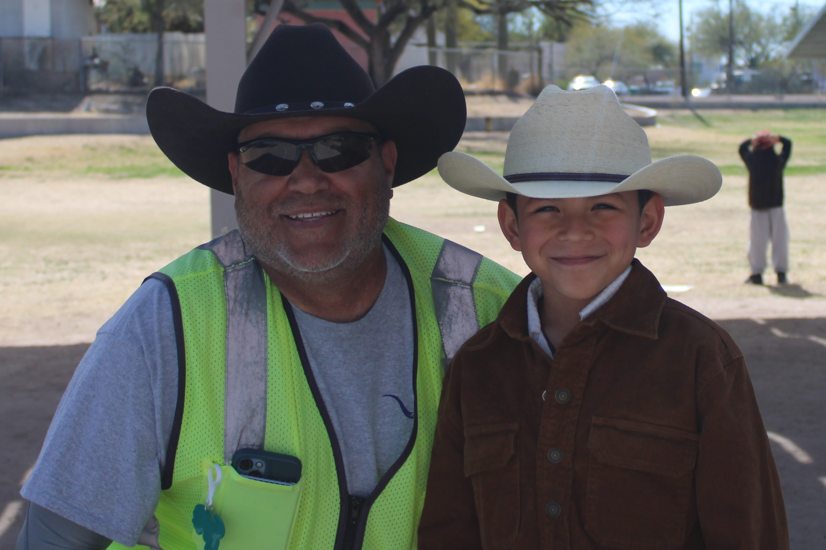 A man and a boy smile in their cowboy hats