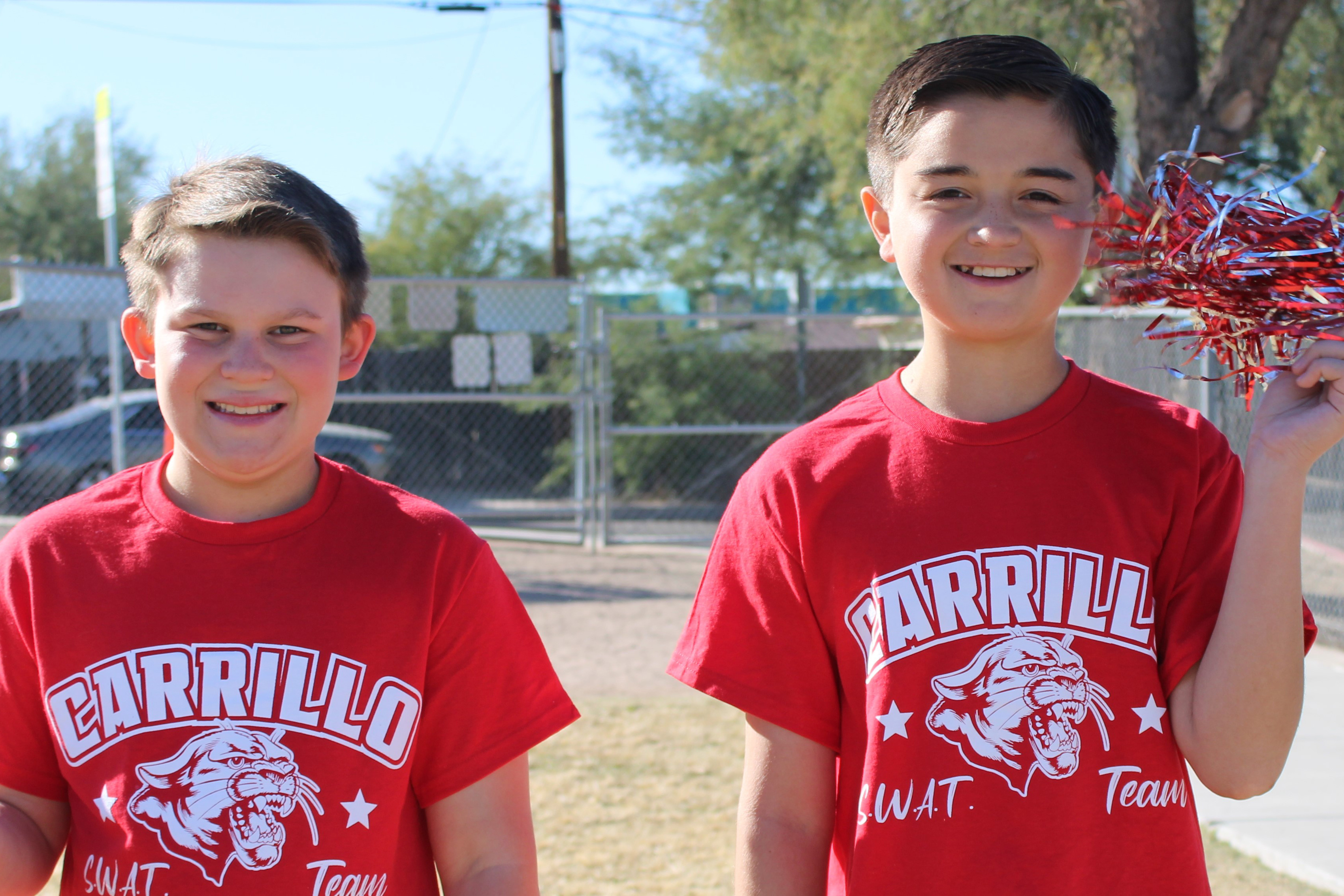 Two boys in red Carrillo shirts smile on the field