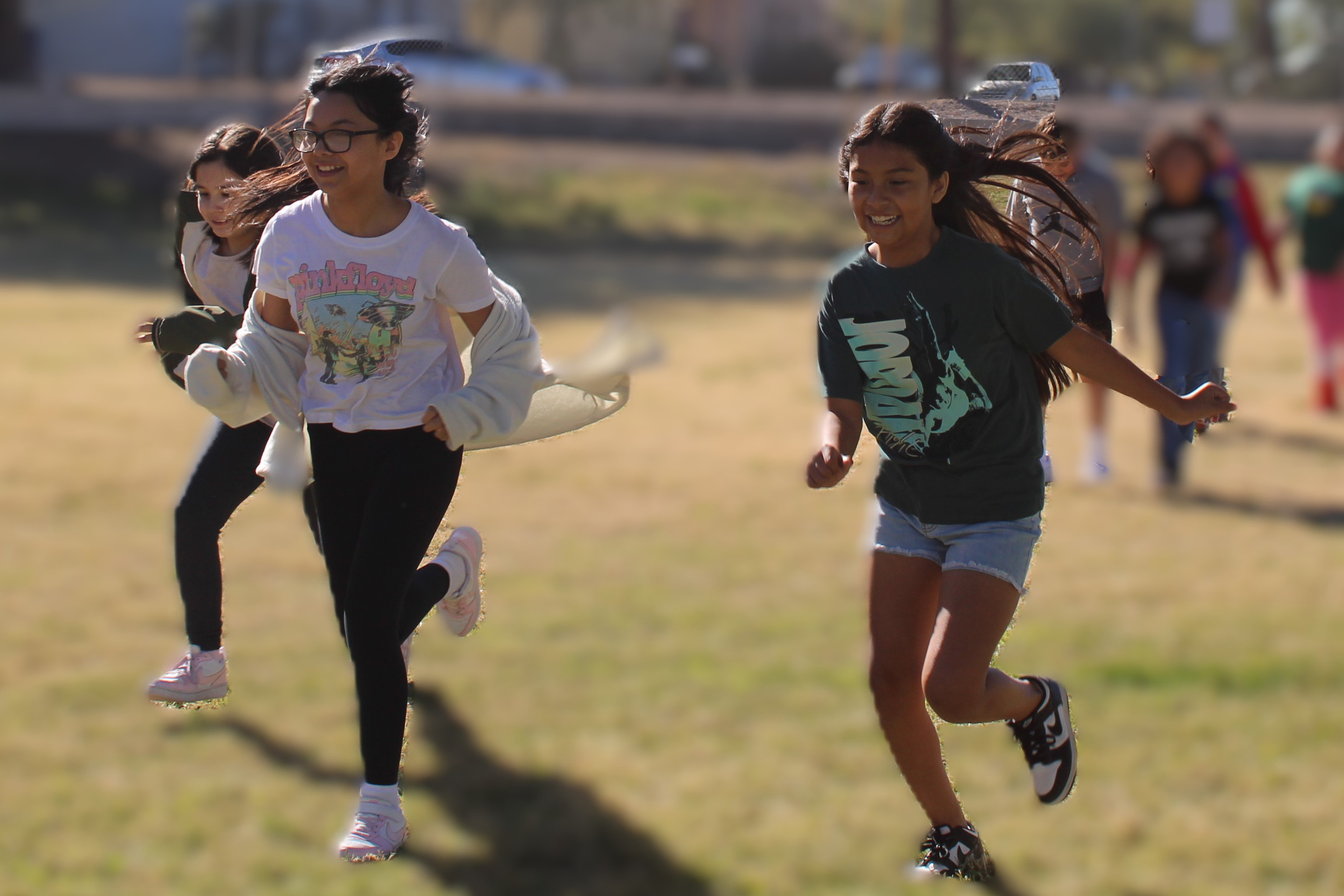 Three girls run across the field