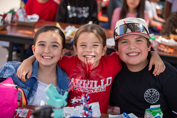 Three friends smile as they enjoy lunch together