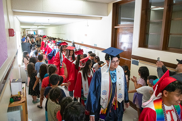Elementary students give high fives to the high school grads as they walk the hallways
