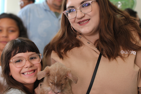 A little girl and woman smile holding a puppy