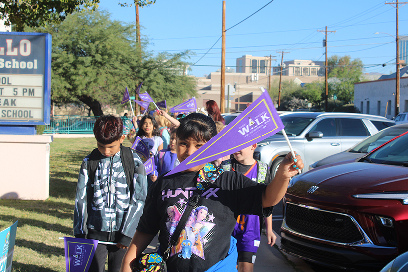 Students walk around campus holding purple Ruby Bridges pennants