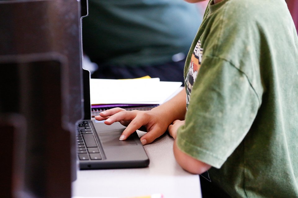 A boy clicks on his laptop trackpad