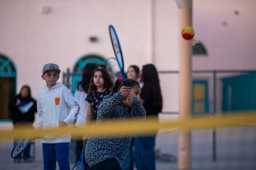 A girl swings at the tennis ball with her racquet