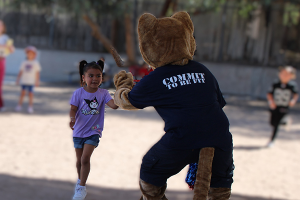 A cougar mascot gives a little girl a fist bump