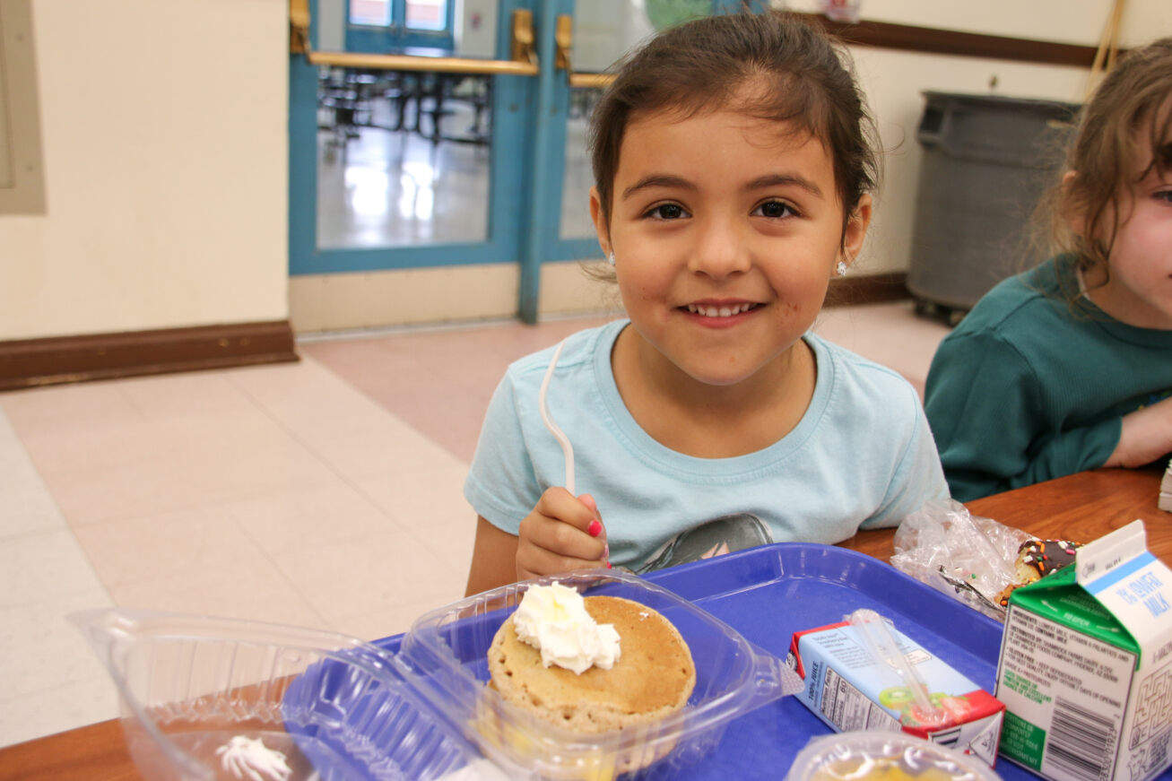 A little girl smiles as she gets ready to dig into her tropical pancakes!