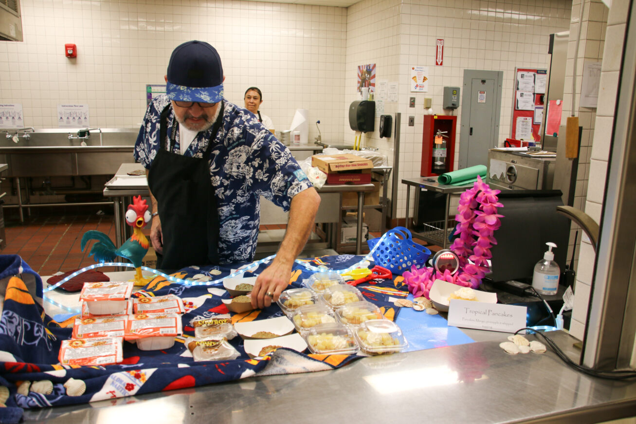 A Food Services employee in a Hawaiian style shirt makes tropical pancakes for students.