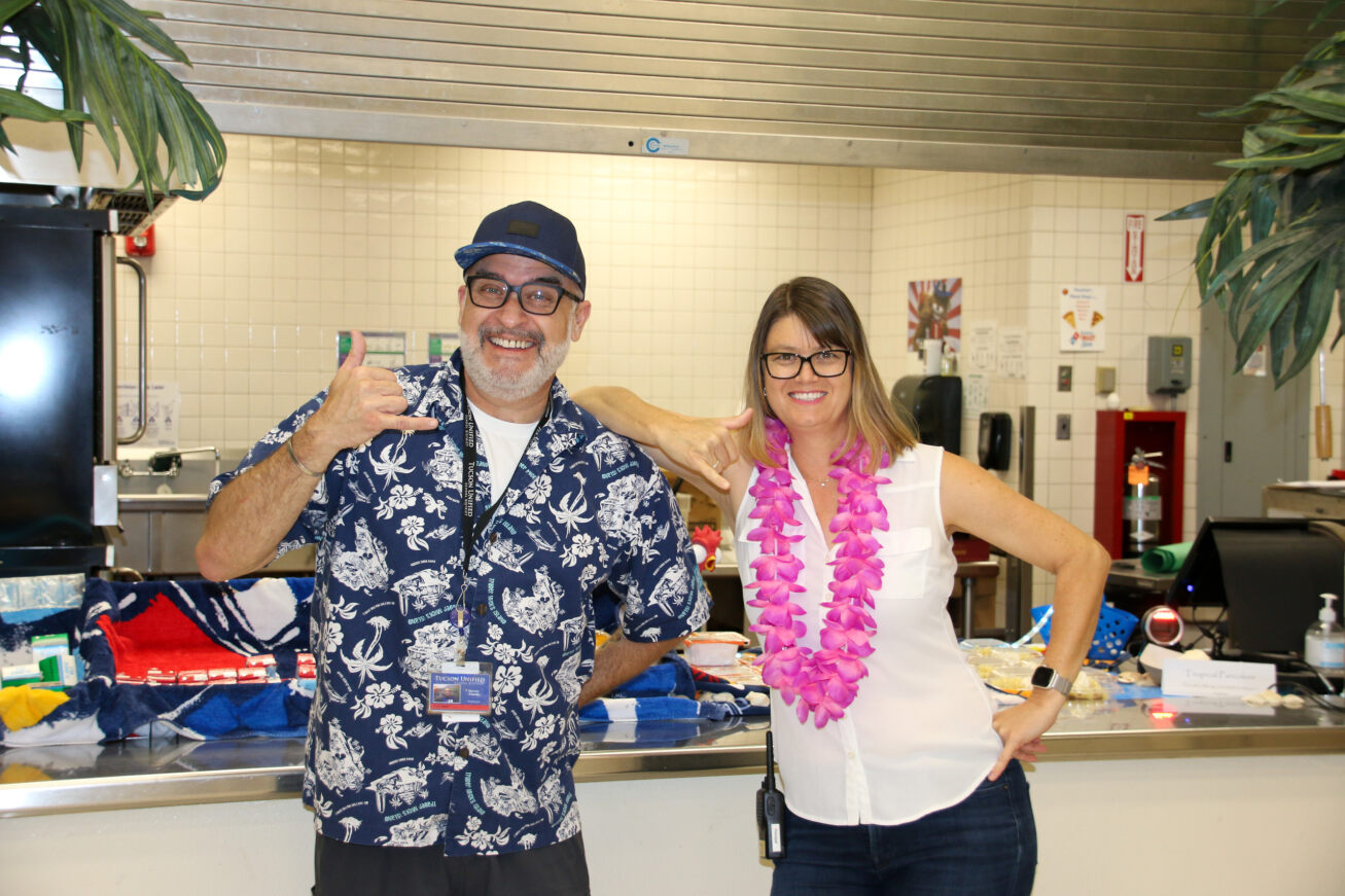 Two Food Services employees in tropical attire smile for a photo!